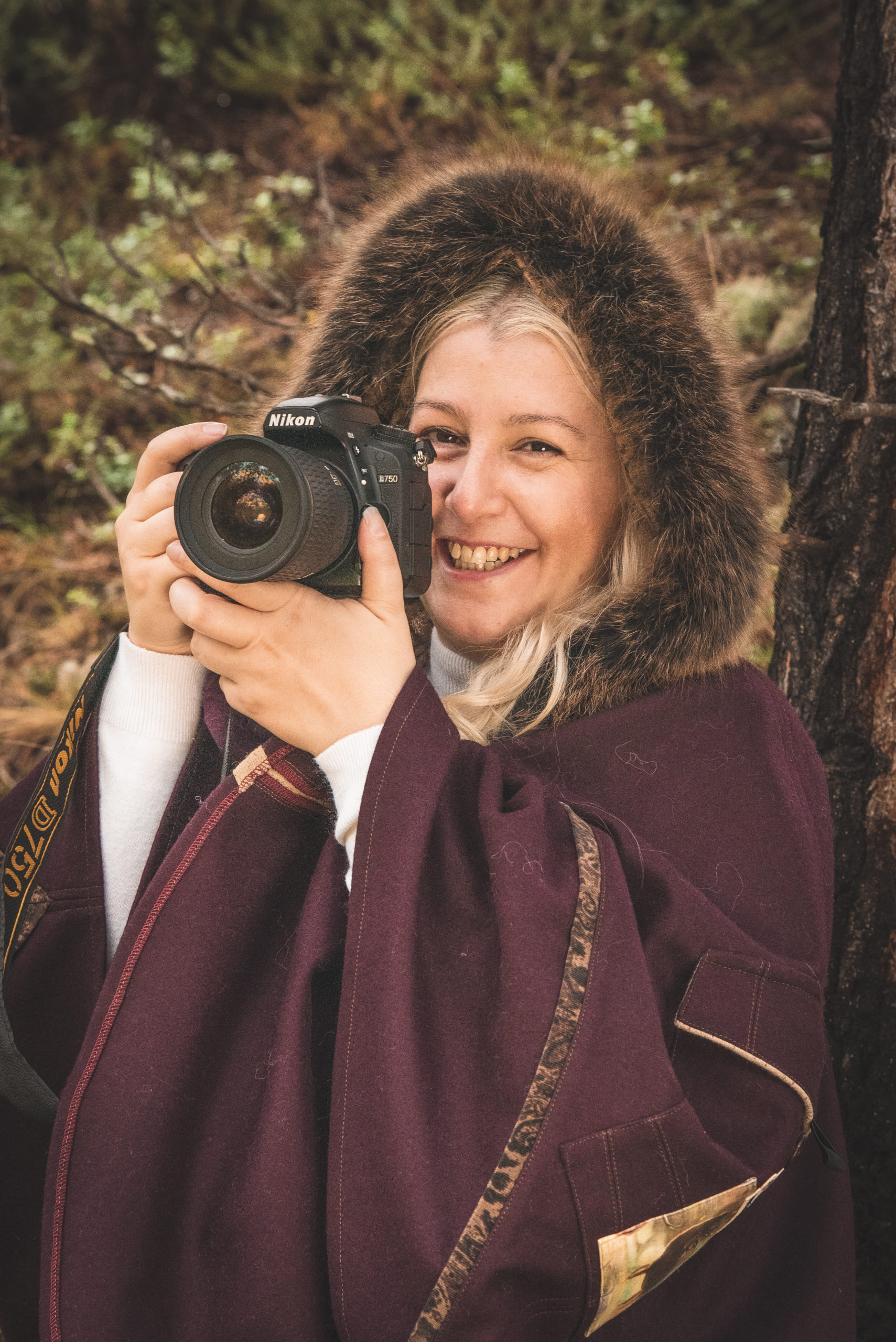 female photographer poses with camera in nature